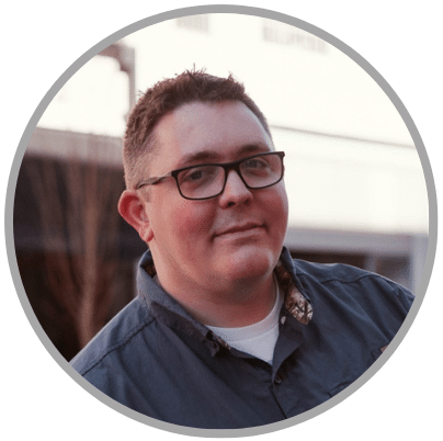 Allen_Payne_Website_Headshot Male wearing gray shirt and glasses smiling